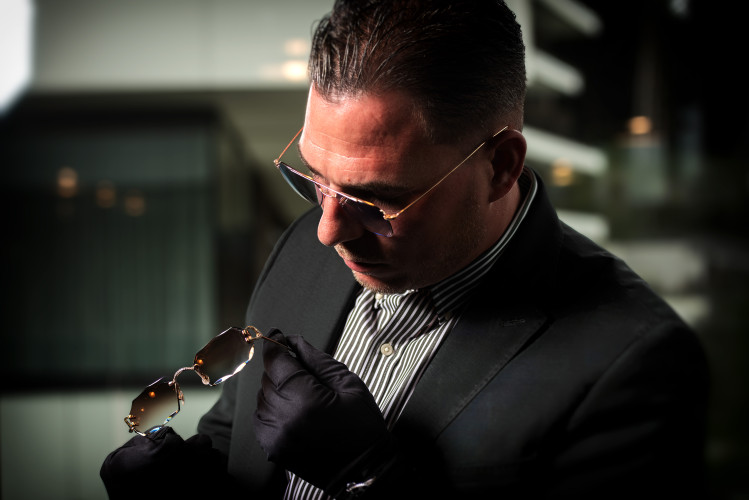 Adrien Pironet inspectant une paire de lunettes haut de gamme avec beaucoup de précautions